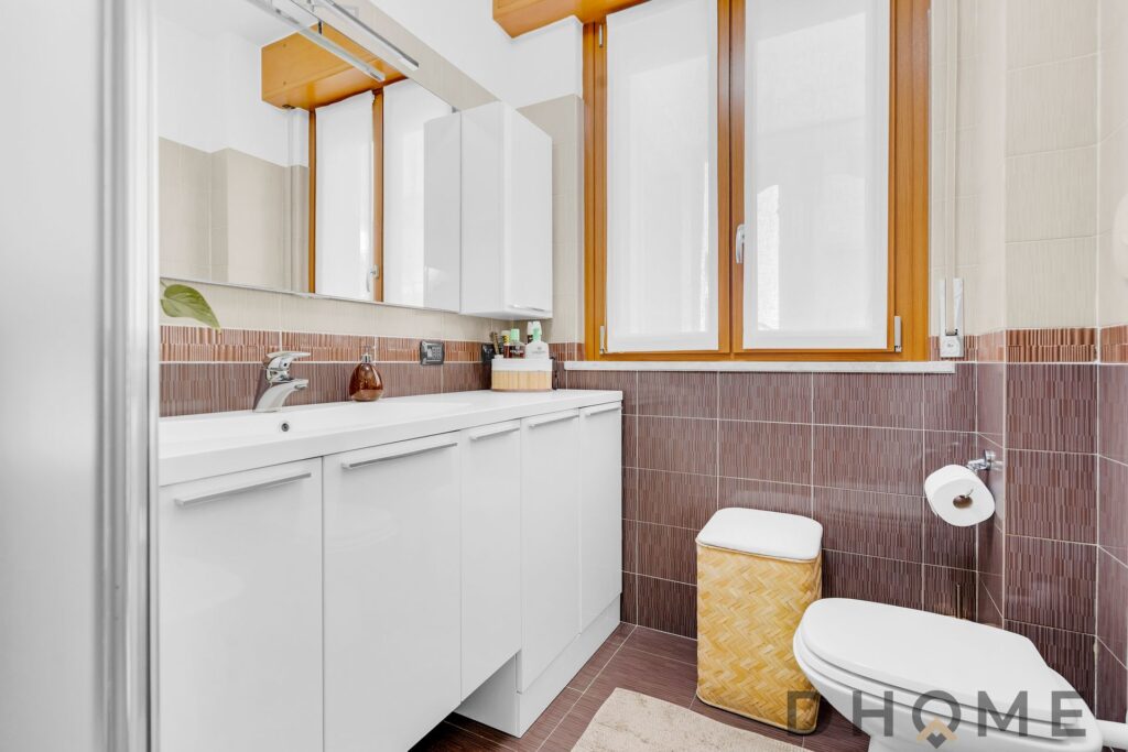 Ampio bagno luminoso con finestra e accessori moderni.