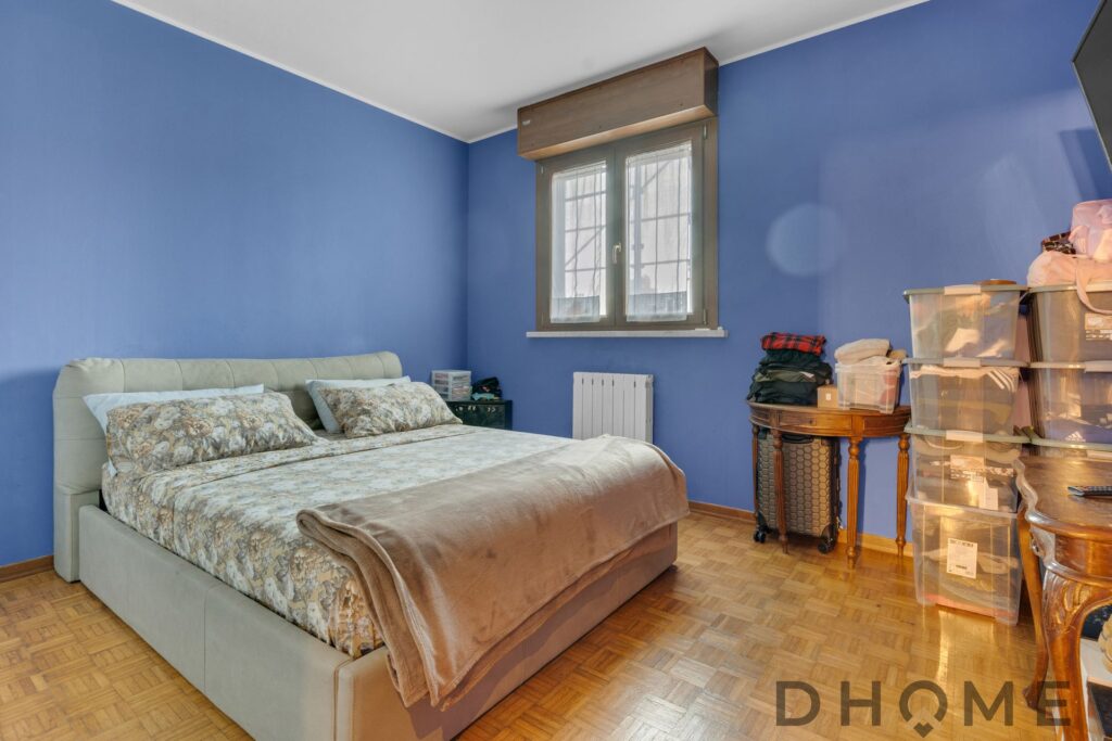 Camera da letto con pareti blu, letto matrimoniale e finestra grande.