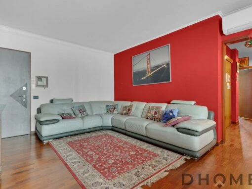 Divano grande in soggiorno con parete rossa e decorazioni moderne.